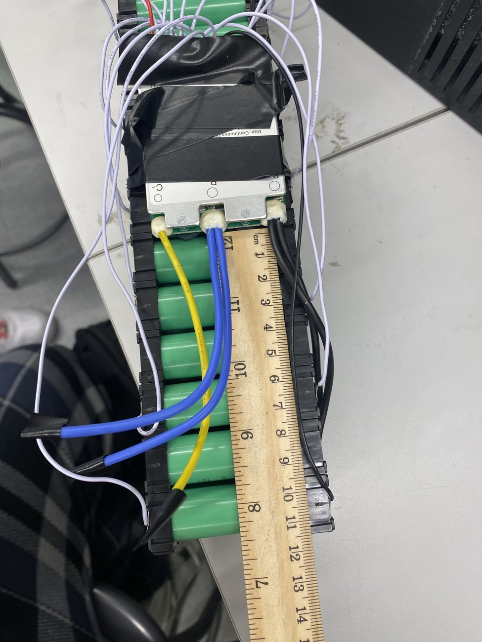 Bare cells and BMS wiring, shown against a ruler for scale.